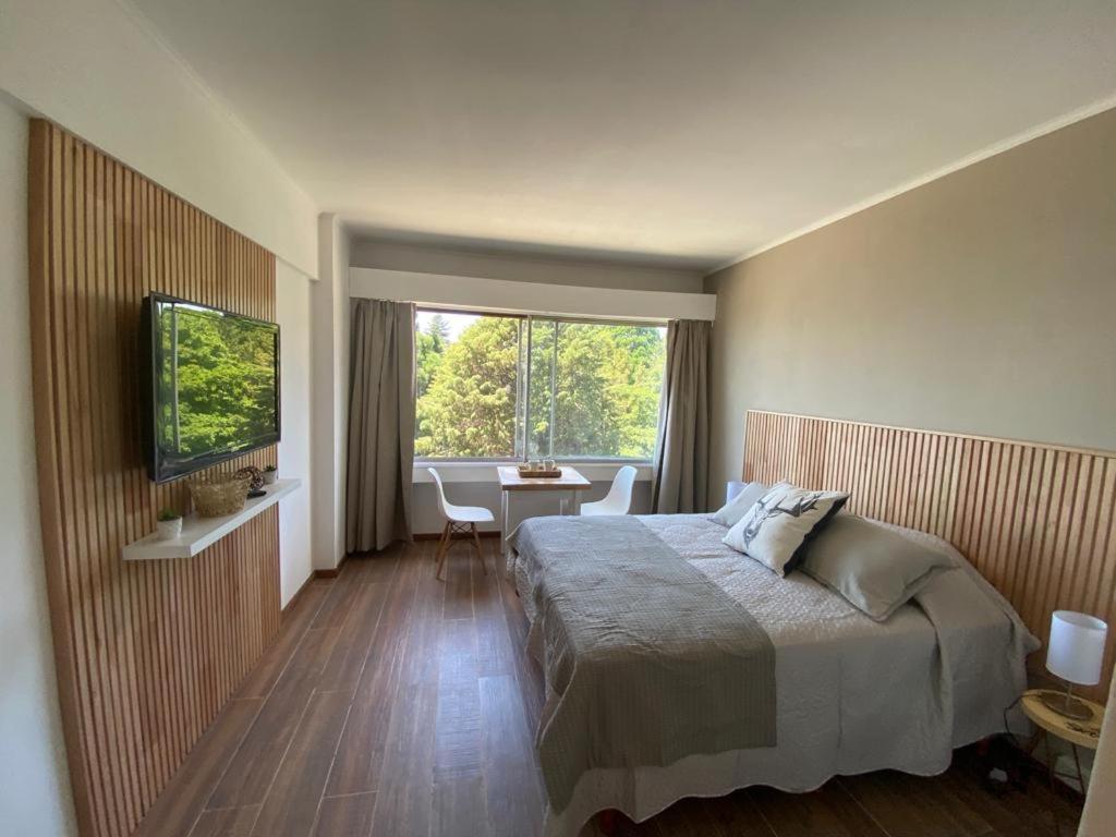 1 dormitorio con cama, mesa y TV en Patagonia Center en San Carlos de Bariloche