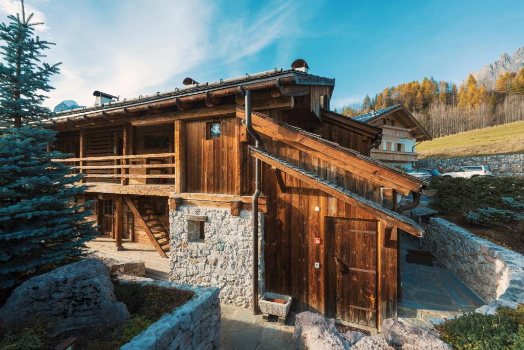 a wooden house with a stone wall at Luxury Cortina in Cortina dʼAmpezzo