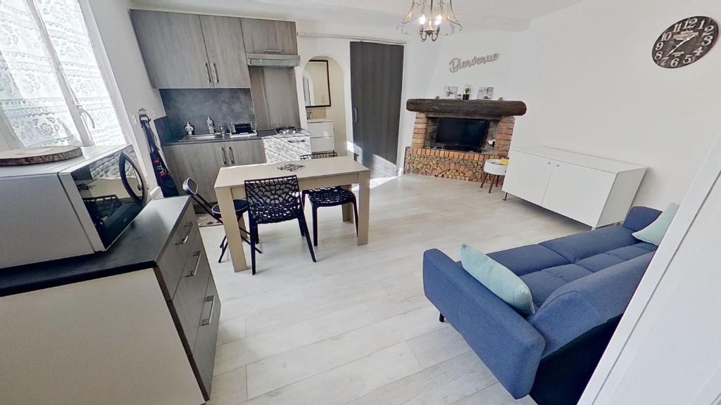 een woonkamer met een blauwe bank en een keuken bij Gîte « l’Escapade Cabassoise » in Cabasse
