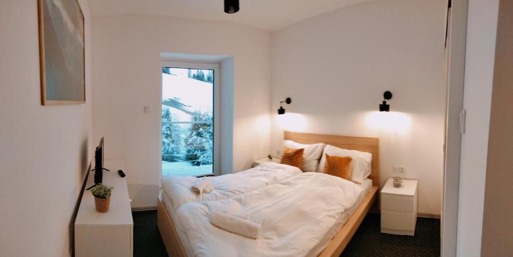 a bedroom with a bed with white sheets and a window at U Gumisia in Korbielów