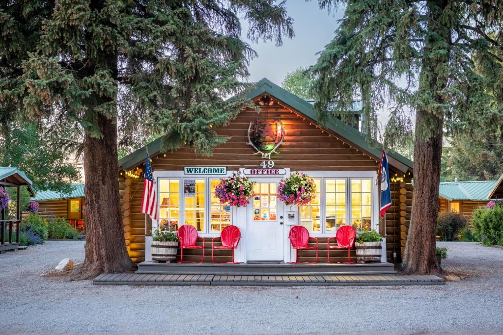 um chalé de madeira com cadeiras vermelhas e uma porta branca em Log Cabin Motel em Pinedale