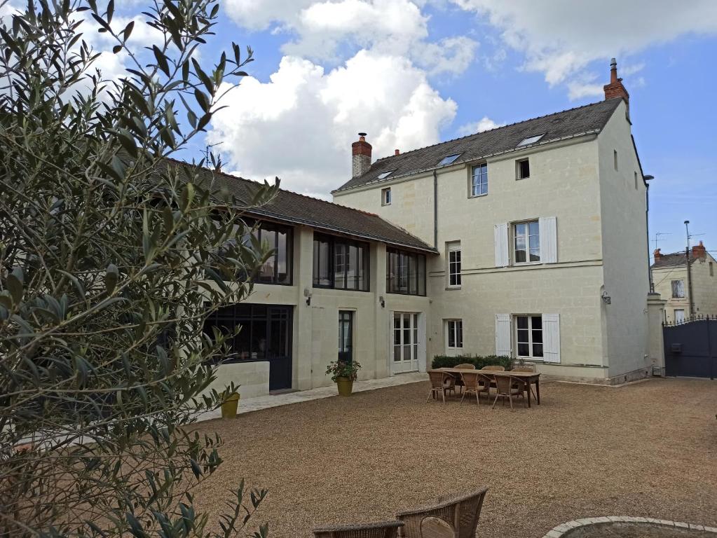 uma grande casa branca com um pátio em frente em La douceur Saumuroise avec petit déjeuner em Saumur