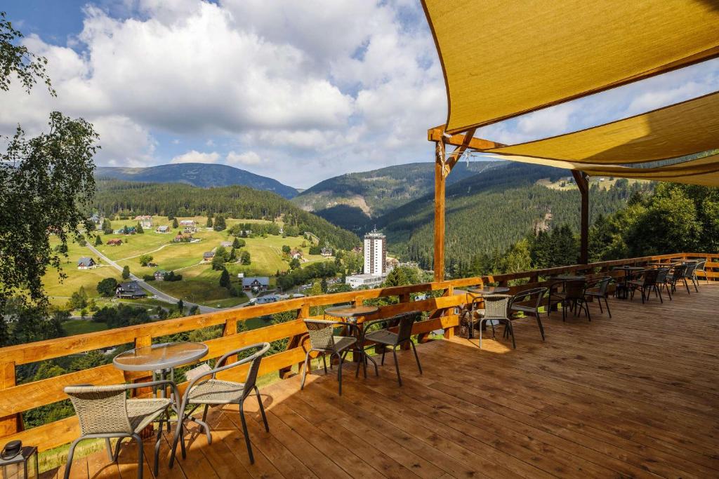 una terraza con mesas y sillas y vistas a las montañas en Chata Orlik - all inclusive & wellness, en Pec pod Sněžkou