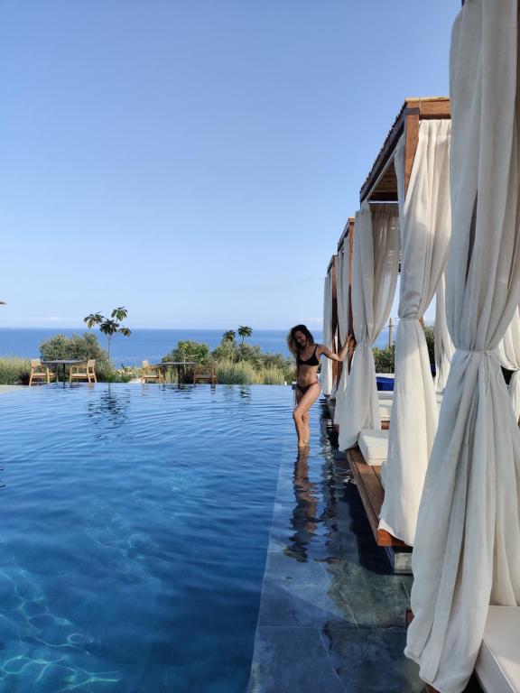 una mujer parada en el costado de un barco en el agua en Panorama Apartments updated with infinity pool en Agios Nikolaos