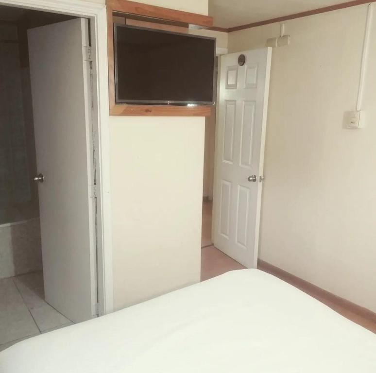 Zimmer mit einem Bett und einem Flachbild-TV in der Unterkunft HOTEL NUNA in Puerto Montt