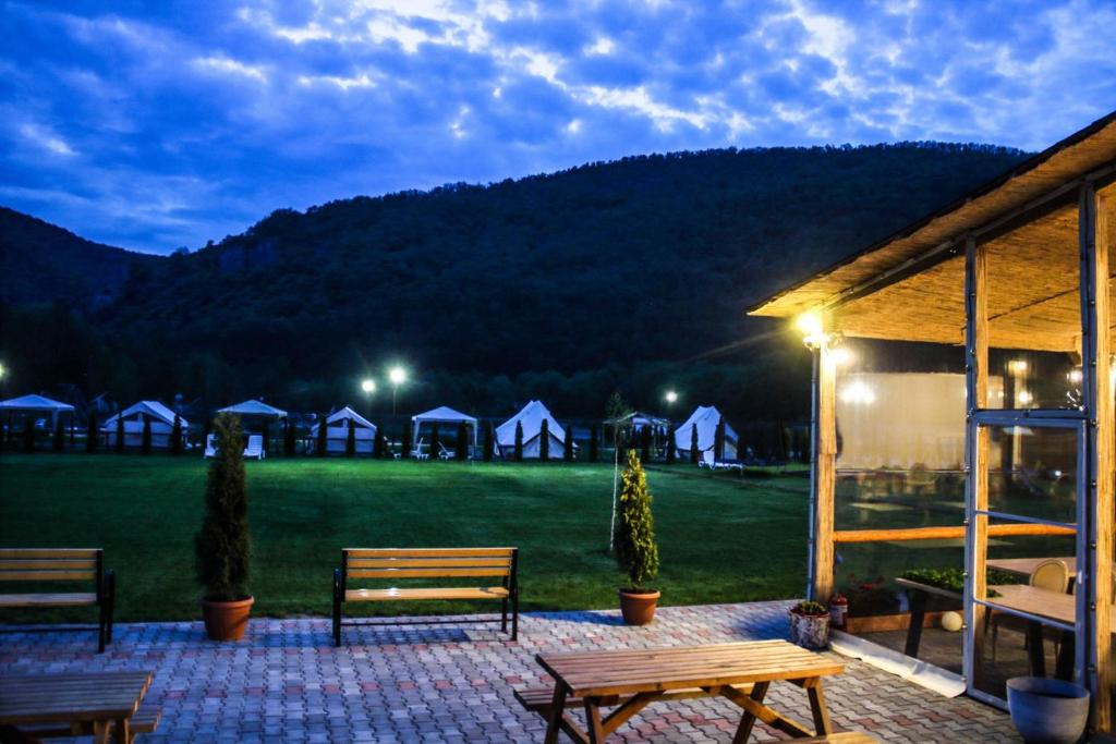 un patio con bancos y un campo verde con tiendas de campaña en Green Resort Suncuius, en Şuncuiuş