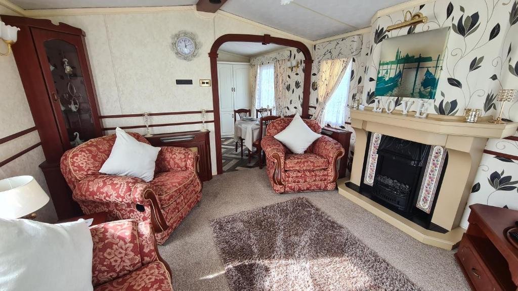 Caravan 6 berth في إنغولدميلز: غرفة معيشة مع كرسيين ومدفأة