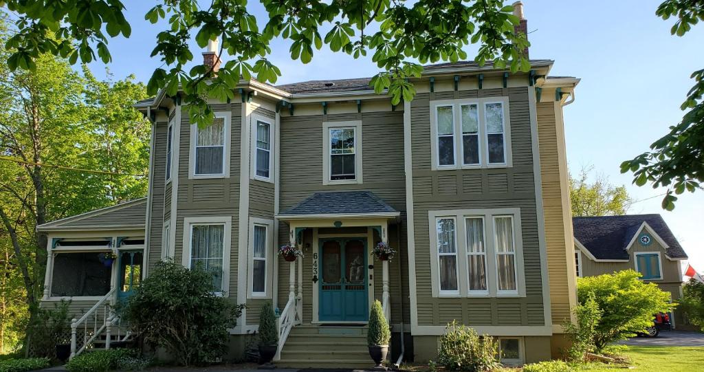 uma casa com uma porta azul e árvores em The Lark & Loon Inn em Annapolis Royal