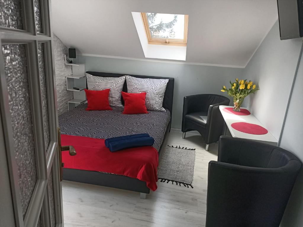 a bedroom with a bed with red pillows and a chair at TOPOLA in Gąski