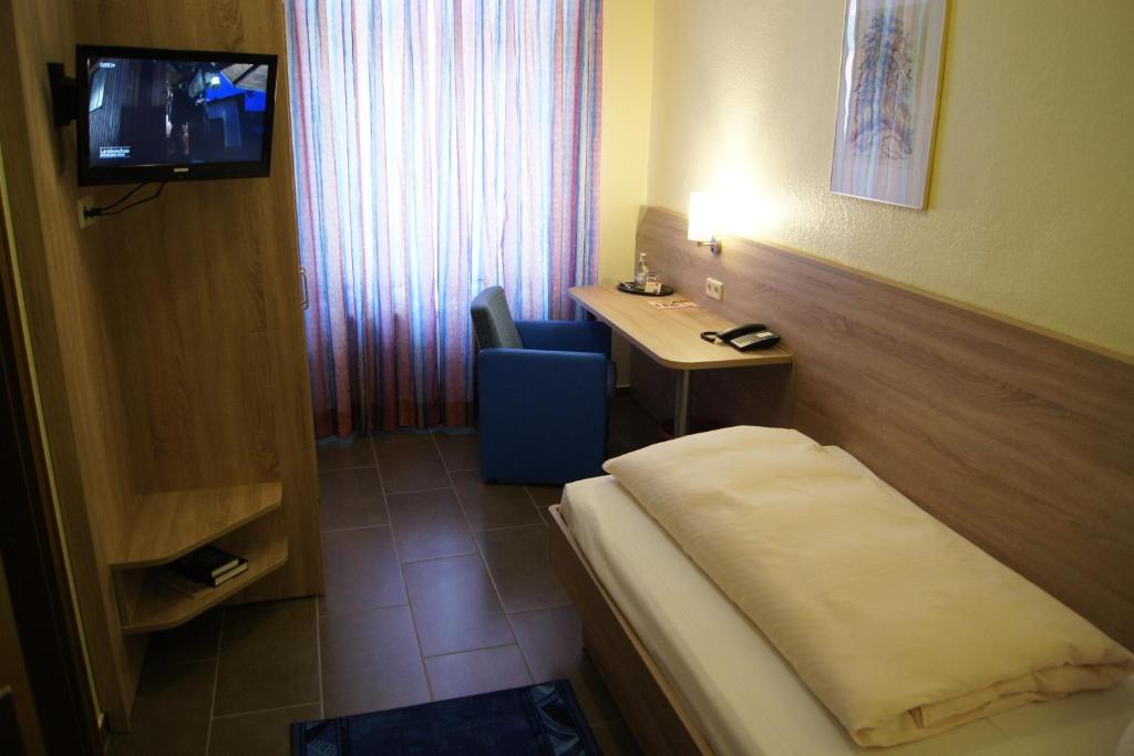 a hotel room with a bed and a desk and a television at Hotel Drei Rosen in Worbis