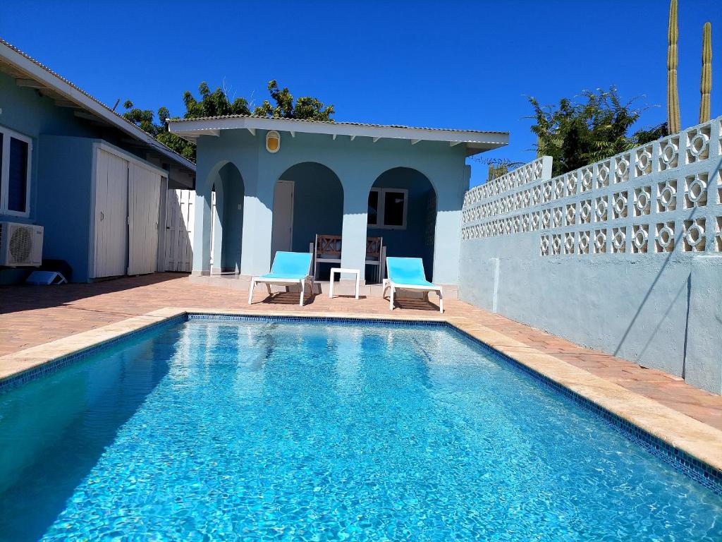 a swimming pool with two chairs and a house at Apartment Villa Valentina in Noord