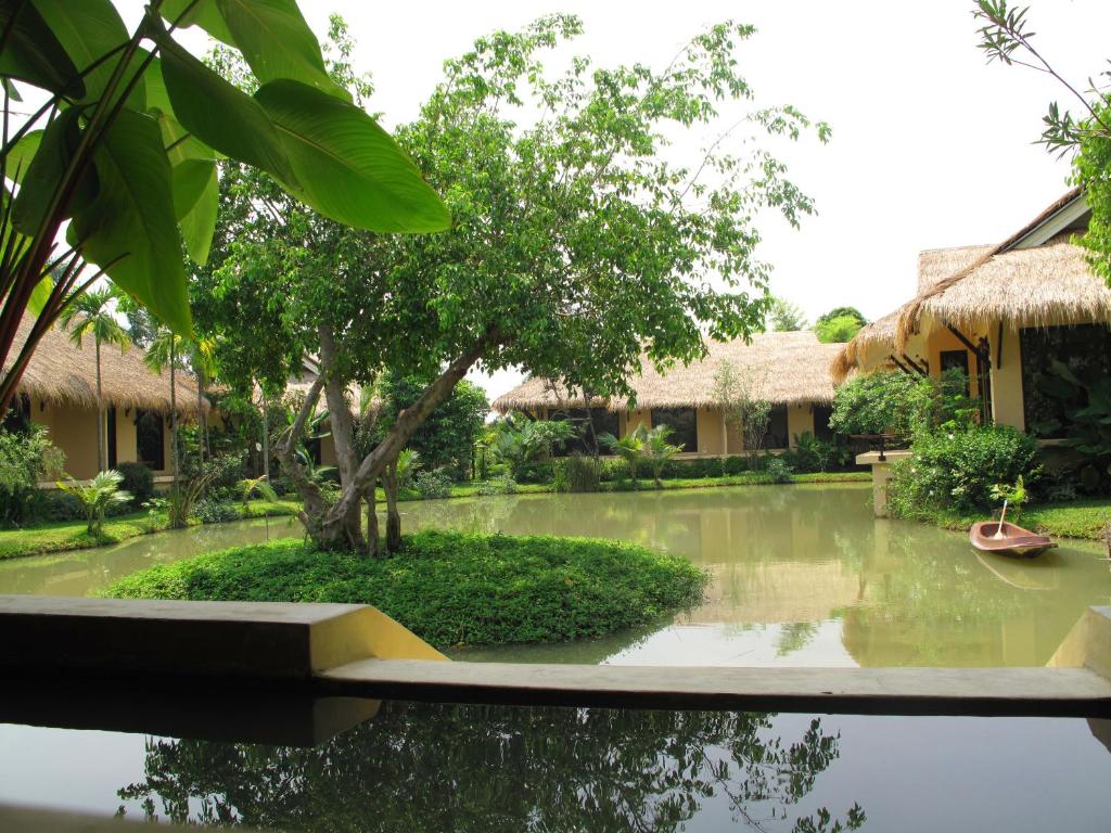 a garden with a pond in front of a building at IngNatee Resort in Pathum Thani