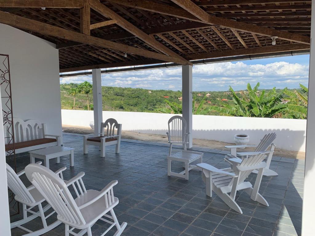 a patio with white chairs and tables and a view at Casa do Vale in Triunfo