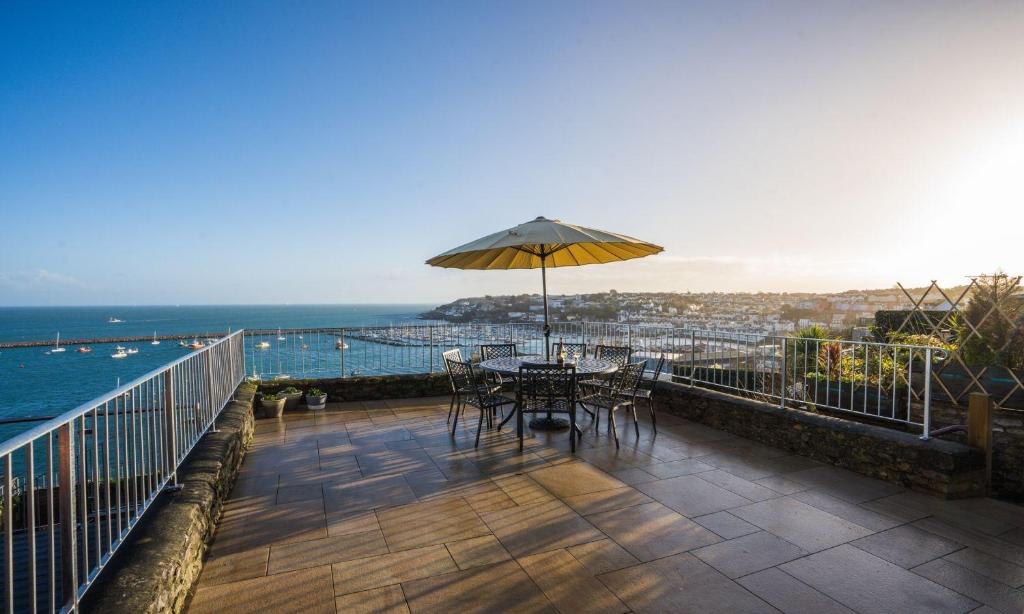 a patio with a table and an umbrella on a balcony at La Mouette in Brixham