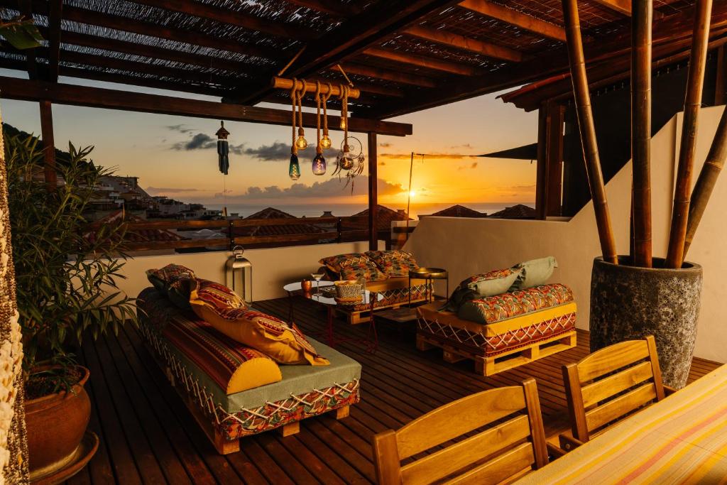 een terras met banken en stoelen en een zonsondergang bij Roque-House in Adeje