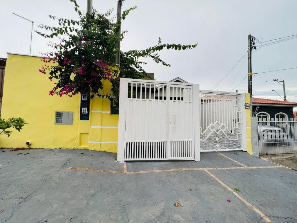 a white gate in a parking lot next to a yellow building at Casa do Henrique 2 in Sorocaba