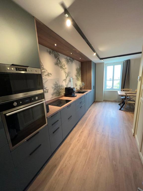 uma grande cozinha com pisos em madeira e um grande aparelho em DUPLEX AVENUE ROYALE em Compiègne