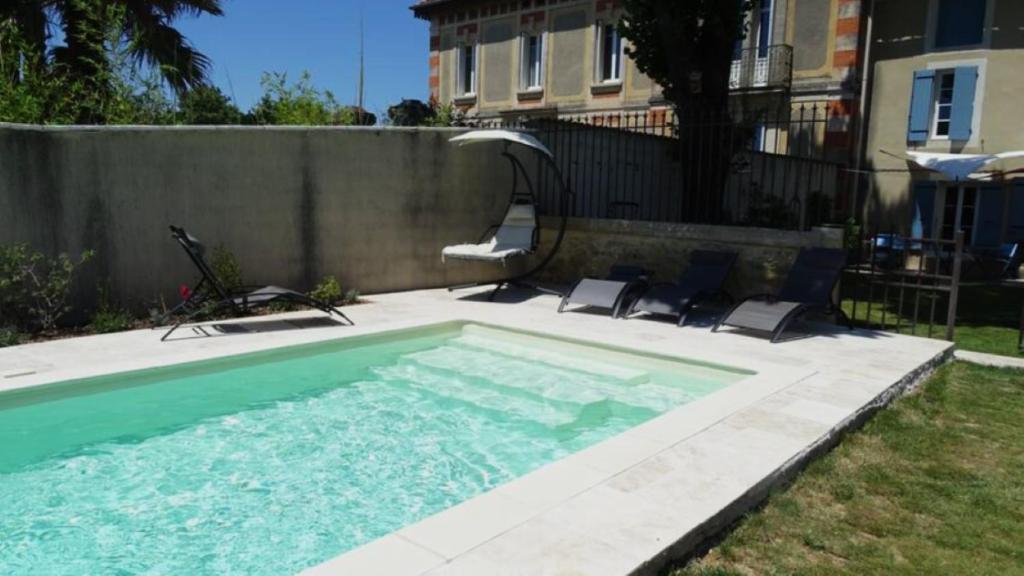 a swimming pool in a yard next to a house at Lou pinsan in Camaret-sur-Aigues