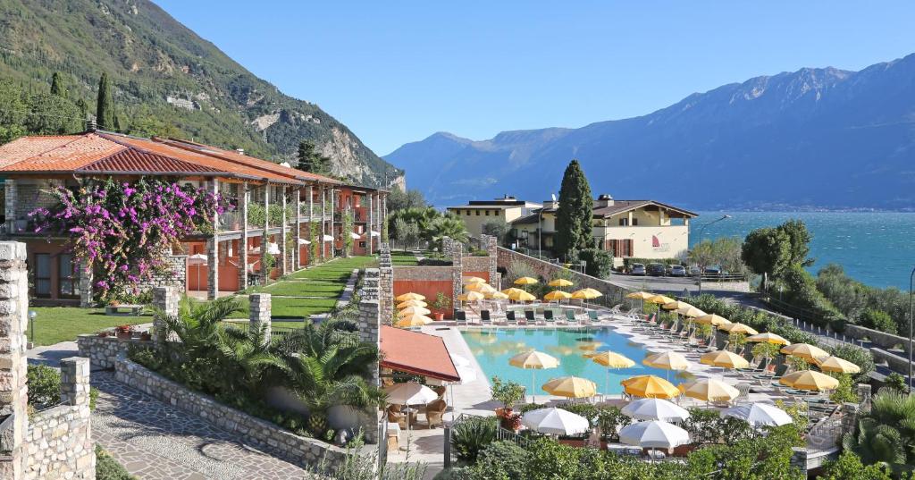 un complexe avec une piscine bordée de parasols dans l'établissement Residence Borgo Dei Limoni - Appartamenti con Garage, à Gargnano