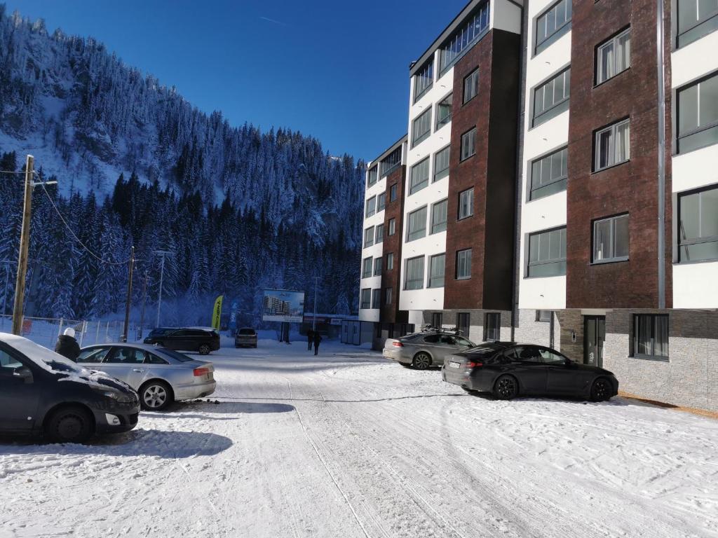a parking lot with cars parked next to a building at Apartman Dream Jahorina Snjezna Dolina in Jahorina
