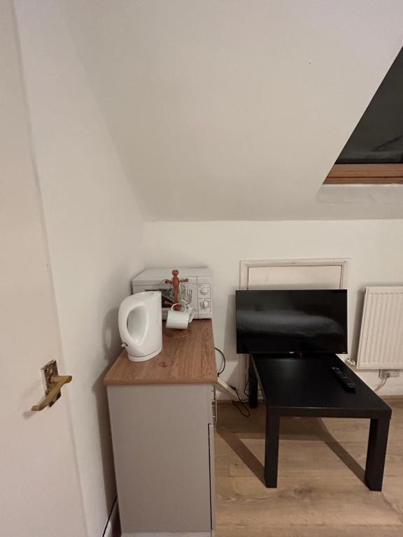 a small kitchen with a table and a piano at Studio Flat In Croydon in Thornton Heath