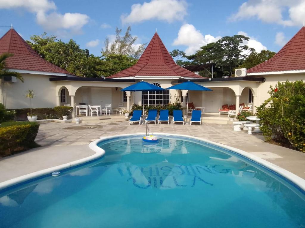 a pool at a resort with blue chairs and umbrellas at Whistling Villa Runaway Bay in Runaway Bay