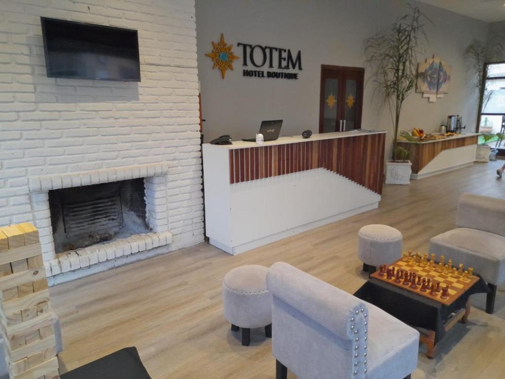 vestíbulo con chimenea, mesa y sillas en Hotel TOTEM Boutique en Termas de Río Hondo