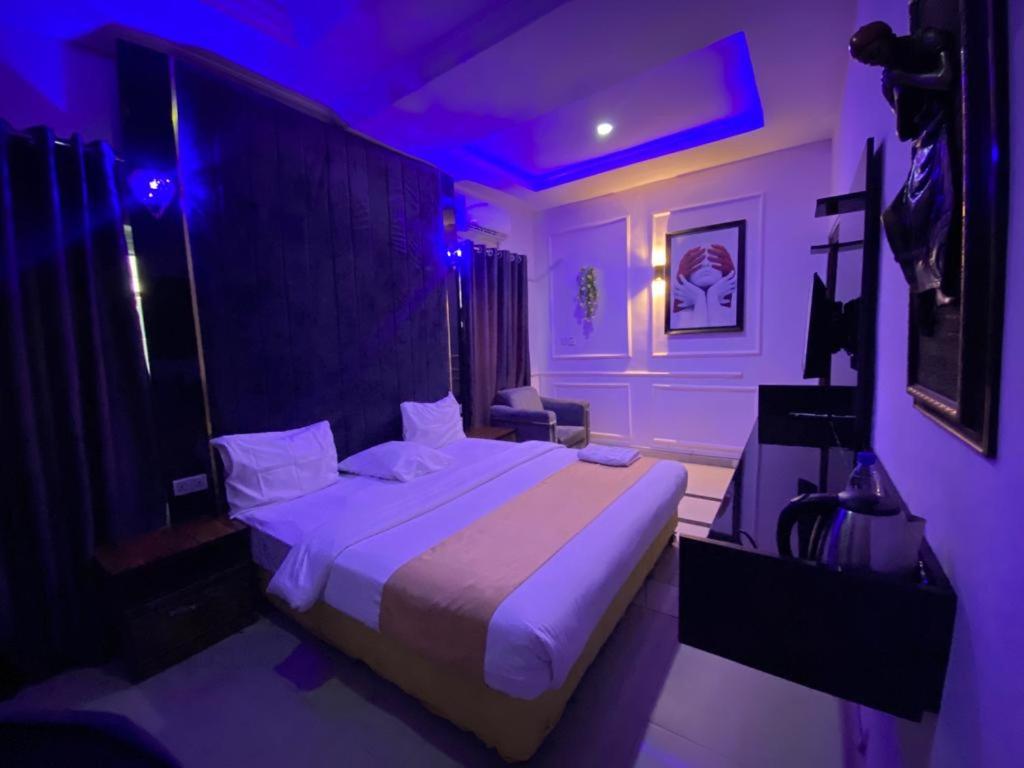 1 dormitorio con 1 cama grande con luces moradas en Palazzo Apartments, en Ikeja