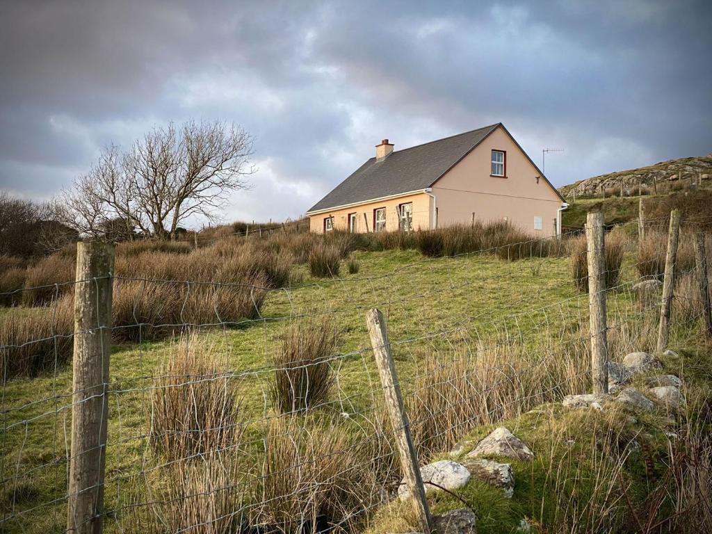 ein Haus auf einem Hügel mit einem Zaun in der Unterkunft Cottage 427 - Clifden in Clifden