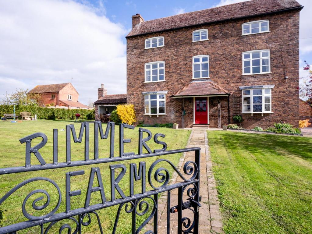 a brick house with a sign in front of it at Rimmers Farmhouse in Wichenford