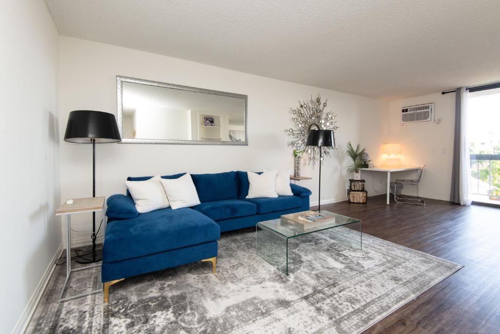 sala de estar con sofá azul y mesa en Prime Location 1-Bedroom with Balcony and Pool, en Los Ángeles