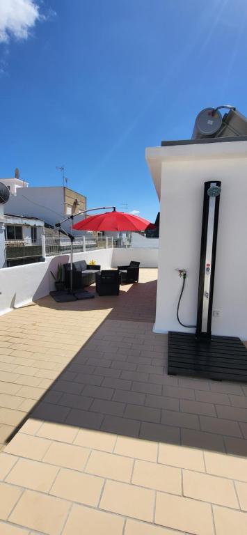 um pátio com mesas e um guarda-chuva vermelho num edifício em RIVERINN Casa Familiar T 3 c Acesso Terraço 1 andar em Portimão