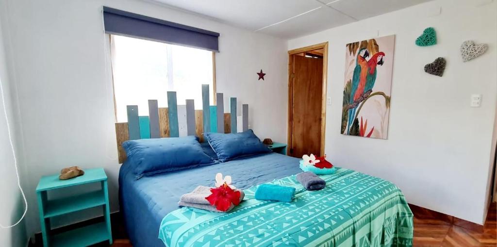 Un dormitorio con una cama azul con toallas. en Henua Roa Loft en Hanga Roa