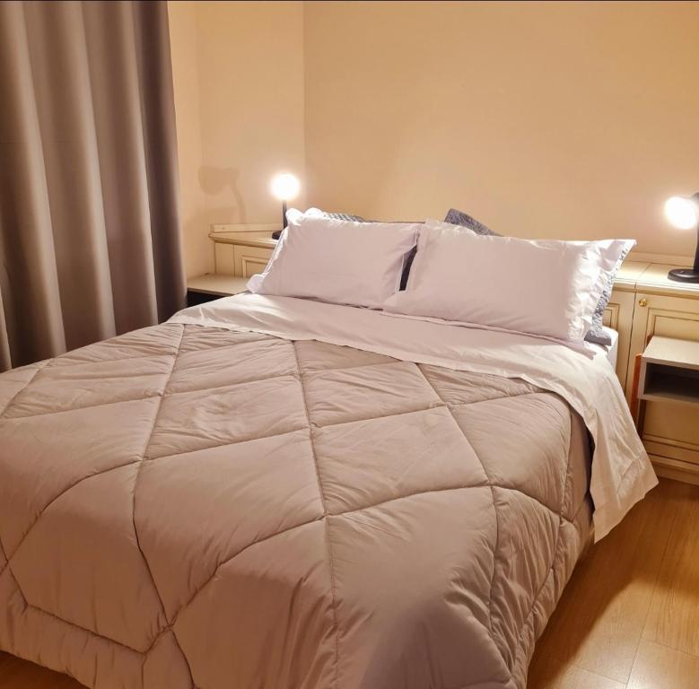 una camera da letto con un grande letto con lenzuola e cuscini bianchi di Apartamento Rua Torta a Gramado