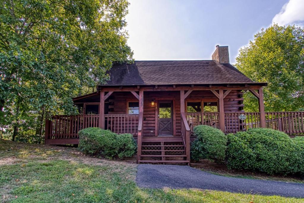 eine Holzhütte mit einer Veranda im Gras in der Unterkunft ER5 - Log Heaven - Great location! Close to all the action! cabin in Pigeon Forge