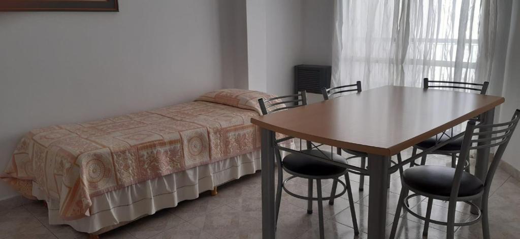 um quarto com uma cama, uma mesa e cadeiras em APART IMPERIO 1 em Río Cuarto
