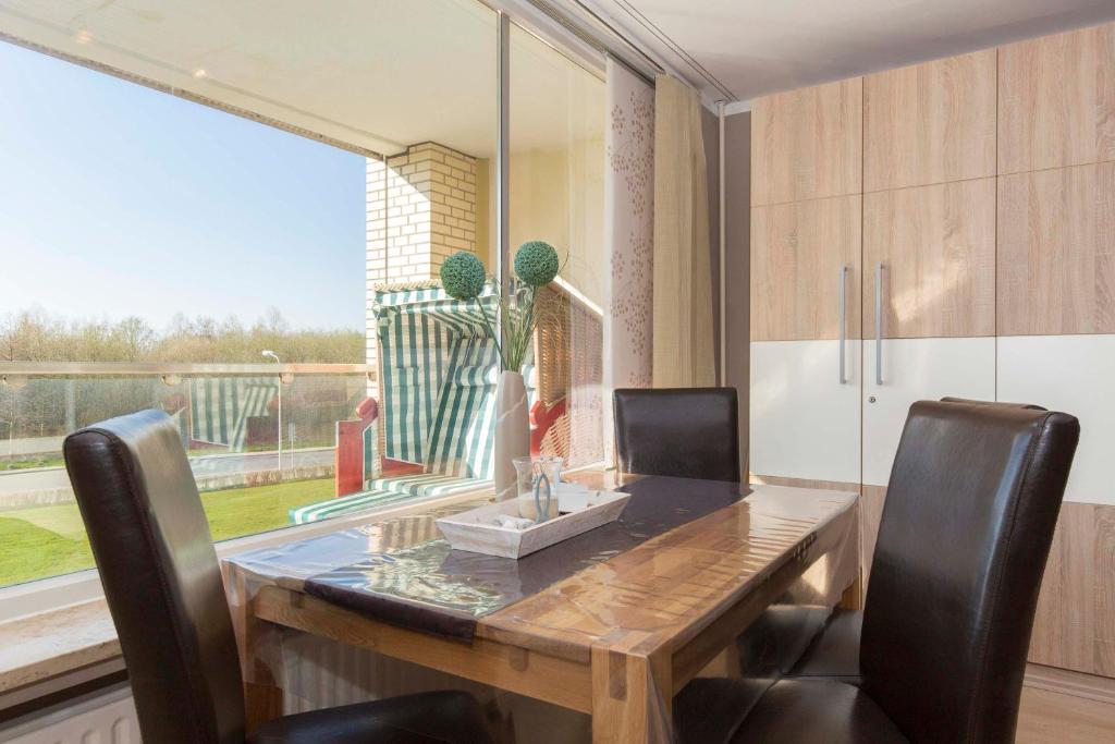 a dining room table with chairs and a large window at Strandhochhaus 5 in Döse