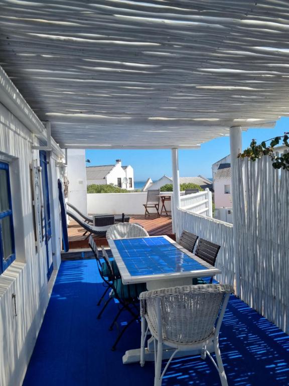 une terrasse couverte avec une table bleue et des chaises. dans l'établissement Mosselbank Beach Retreat 3, à Paternoster