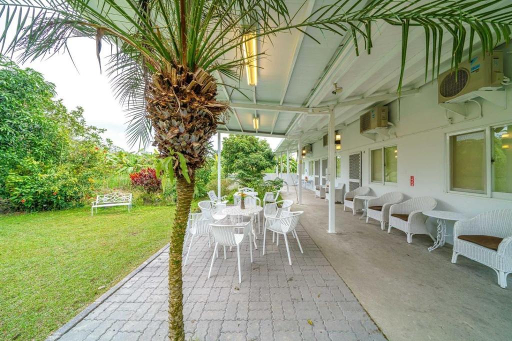 a restaurant with white tables and chairs and a palm tree at Cloud Sun Homestay in Zhixue