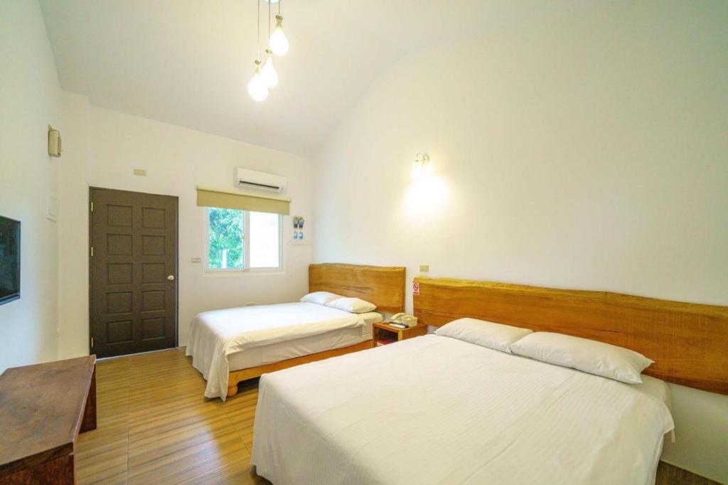 a hotel room with two beds and a door at Cloud Sun Homestay in Zhixue