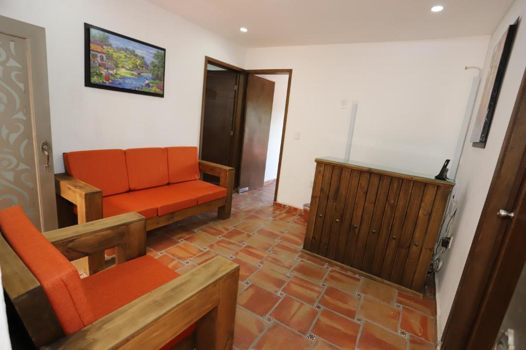 een woonkamer met een oranje bank en een televisie bij Hotel Boutique Casa Elefante in Guadalajara