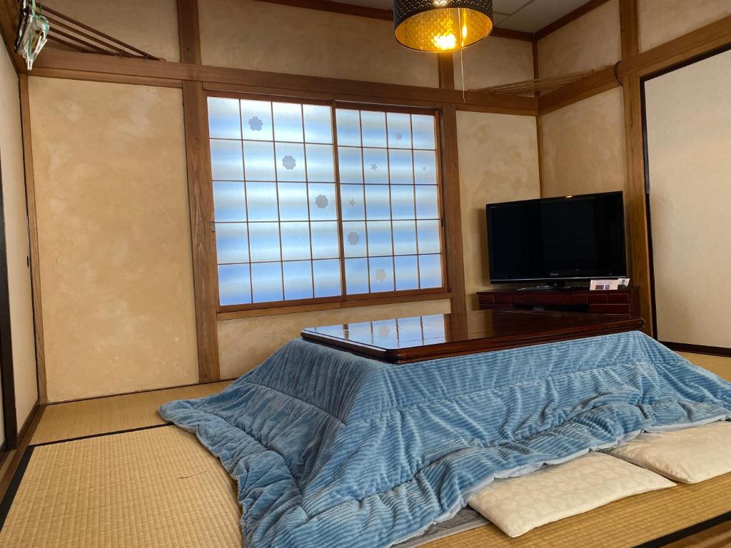 a living room with a bed and a television at Ishimaru House in Seki