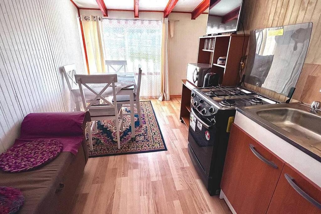 eine Küche mit Herd und Sofa in einem Zimmer in der Unterkunft Acogedor departamento interior, a minutos del Lago in Llanquihue