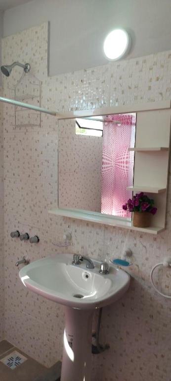 y baño con lavabo blanco y espejo. en Departamento 2 dormitorios Villa Carlos Paz en Villa Carlos Paz