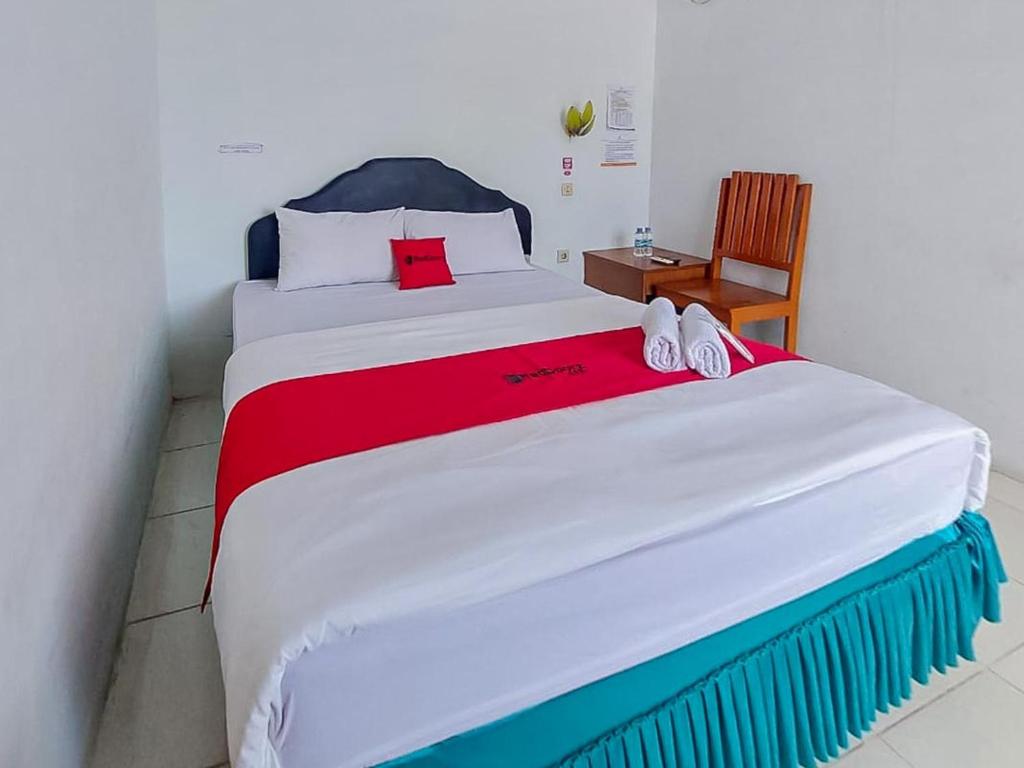 a bedroom with a large bed with a red blanket at RedDoorz @ Tanjung Selor in Tanjungselor