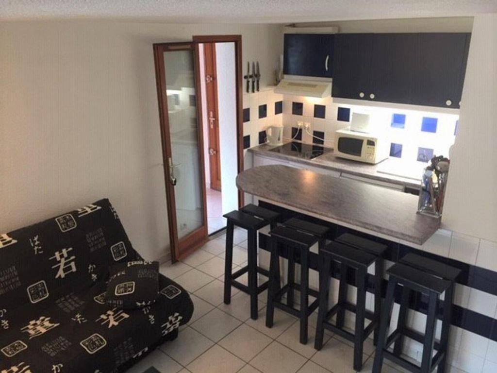 kuchnia z blatem i stołkami w pokoju w obiekcie Pavillon lumineux 3 pièces avec piscine - 6 couchages, proche mer et commerces, parking privé - FR-1-229-818 w mieście Gruissan