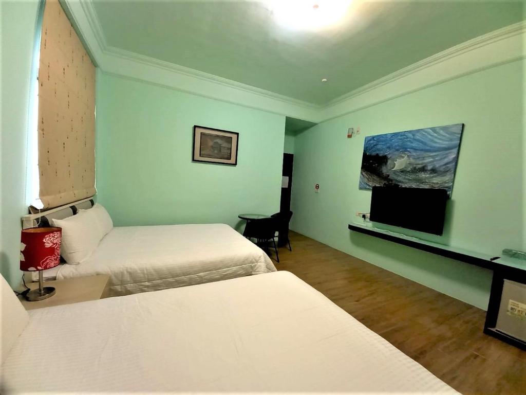 a room with two beds and a flat screen tv at Dreamily Fish B&amp;B in Magong