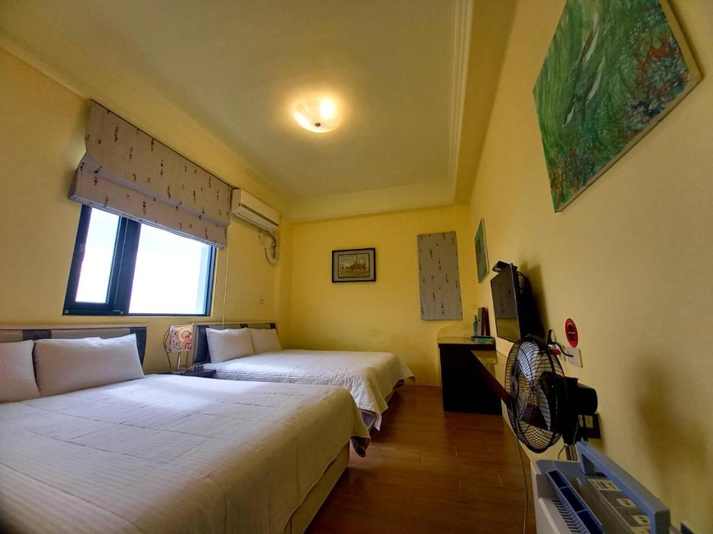 a bedroom with two beds and a tv and a window at Dreamily Fish B&B in Magong