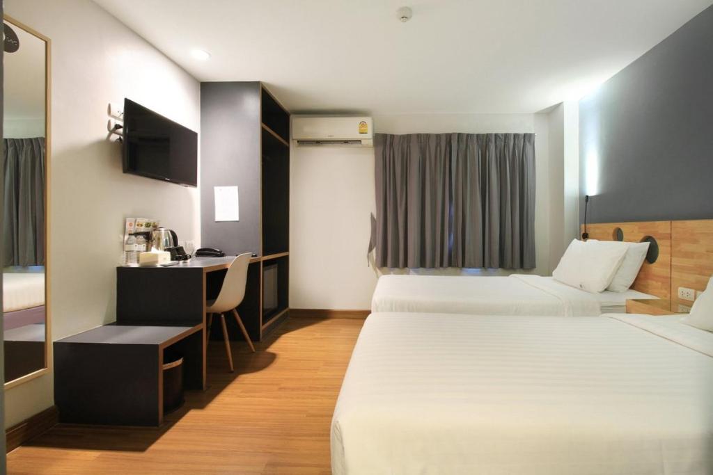 a hotel room with two beds and a desk at Mybed Sathorn Hotel in Bangkok