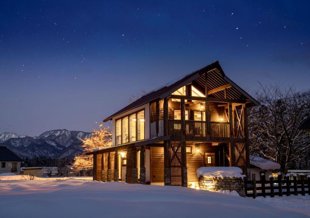 une cabane en rondins dans la neige la nuit dans l'établissement 　白馬　コテージ　チェスナッツ, à Hakuba